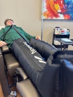 Image of a person using Normatec Compression Therapy apparatus from a side laying angle